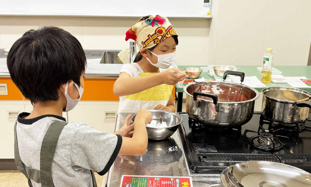 砂糖を鍋に入れる子供