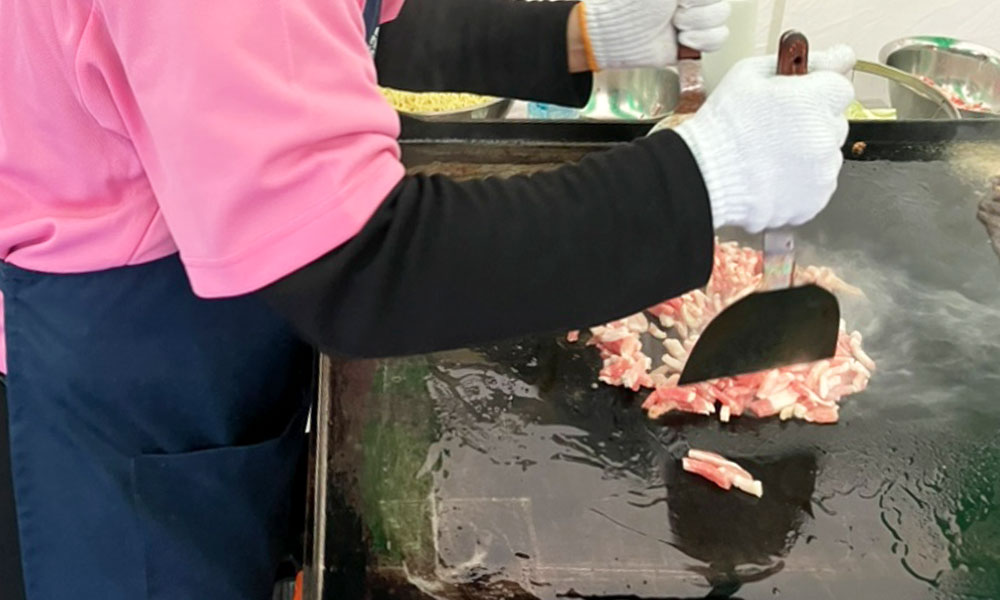 鉄板で豚バラ肉を炒める様子